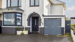 A two-story house with a dark front door, large windows, and a garage. - A beautifully presented, spacious holiday home. (Newquay)