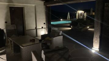 Ein Patio im Freien mit Korbmöbeln, einem Pool und Blick auf den Nachthimmel.