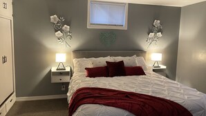 A bedroom with a bed, two nightstands, a window, and decorative wall art. - Brighten Your Day Getaway (Rexburg)