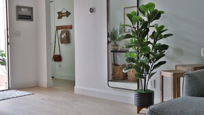 Een moderne woonkamer met een grote spiegel, een potplant en een grijze bank.