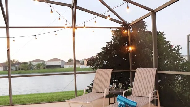 Een overdekt terras met twee loungestoelen, een klein tafeltje en lichtjes.