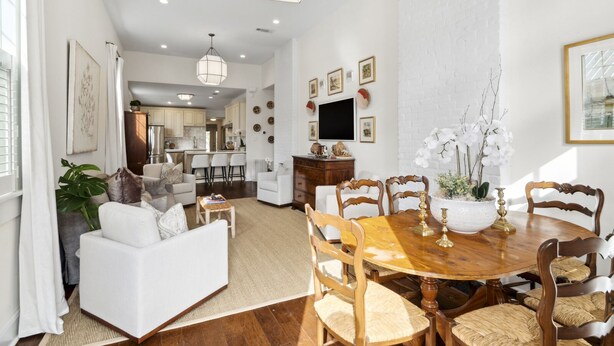 A spacious living room with a dining area, kitchen, and a large window.