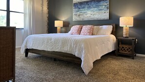 Quarto com uma cama grande, duas luminárias de cabeceira, um ventilador de teto e um quadro na parede.