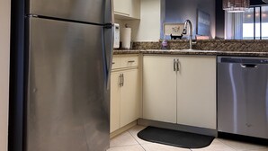 Uma cozinha moderna com eletrodomésticos de aço inoxidável, armários em tons claros e bancada de granito.