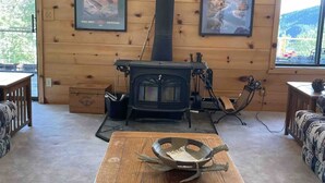 A cozy cabin interior with a wood-burning stove, framed artwork on the walls, and a wooden table in the center. - Cozy Lakeview Cabin outside Jackson Hole
Pallisades Reservoir (Irwin)