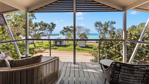 A covered outdoor area with wicker furniture, a view of the sea, and a grassy lawn. - Discovery Parks - Broome (Broome)