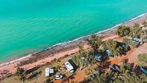 An aerial view of a coastal area with a beach, RVs, and mobile homes. - Discovery Parks - Broome (Broome)