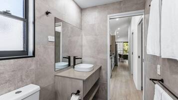 Een moderne badkamer met een grote spiegel, twee wastafels en een toilet.