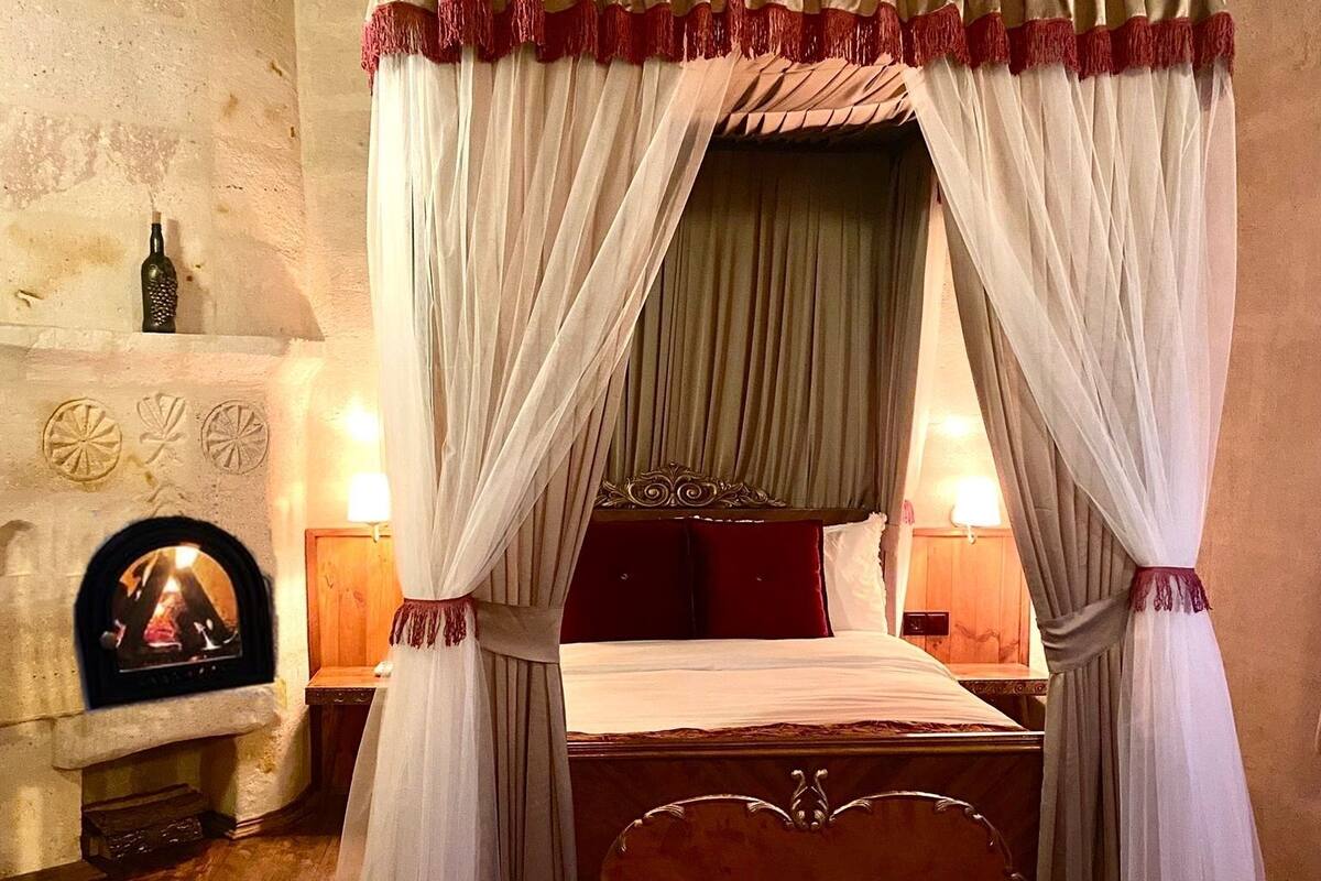 A bedroom with a four-poster bed, a fireplace, and a decorative rug.