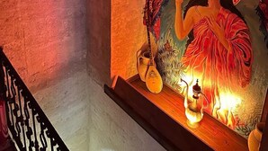 A room with a mural of a woman, a small table with a lamp, and hanging lanterns. - Yohannes Stone Cappadocia (Ürgüp)
