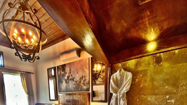 A spacious room with a large bed, a separate sitting area, a bathtub, and a wooden ceiling. - Yohannes Stone Cappadocia (Ürgüp)