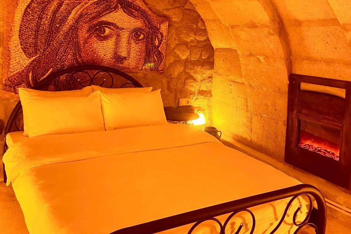A bed in a stone-walled room with a mosaic artwork above it.