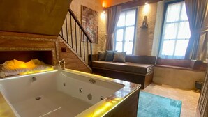 A spacious bathroom with a large bathtub, a wooden bench, and a staircase. - Yohannes Stone Cappadocia (Ürgüp)
