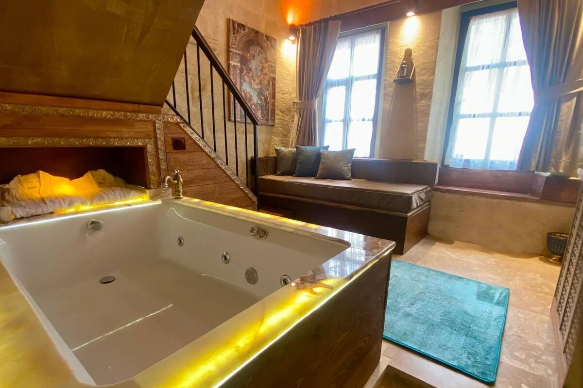 A spacious bathroom with a large bathtub, a wooden bench, and a staircase.