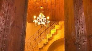 A grand staircase with ornate railings, a chandelier, and a sign indicating a restaurant. - Yohannes Stone Cappadocia (Ürgüp)