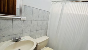 Een badkamer met een wastafel, toilet en douchegordijn.
