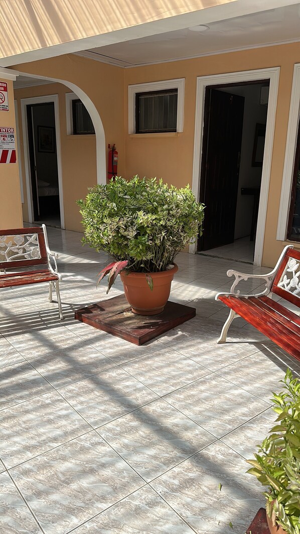 A potted plant in the center of a tiled patio area with two benches on either side. - Hotel Cabinas El Coral (Jacó)