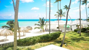 Blick auf einen Strand mit Palmen, einem weißen Gebäude und blauem Himmel.