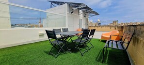 A rooftop terrace with artificial grass, a table with chairs, and a bench. - Traditional Corner Townhouse for rent. Ideal for Groups or Families! (Bormla)