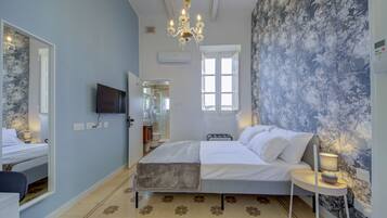 Une chambre à coucher avec un lit, une table de chevet avec une lampe, un téléviseur fixé au mur et une fenêtre.