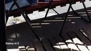A balcony with a table and chairs, a bottle of wine, and a glass of water.