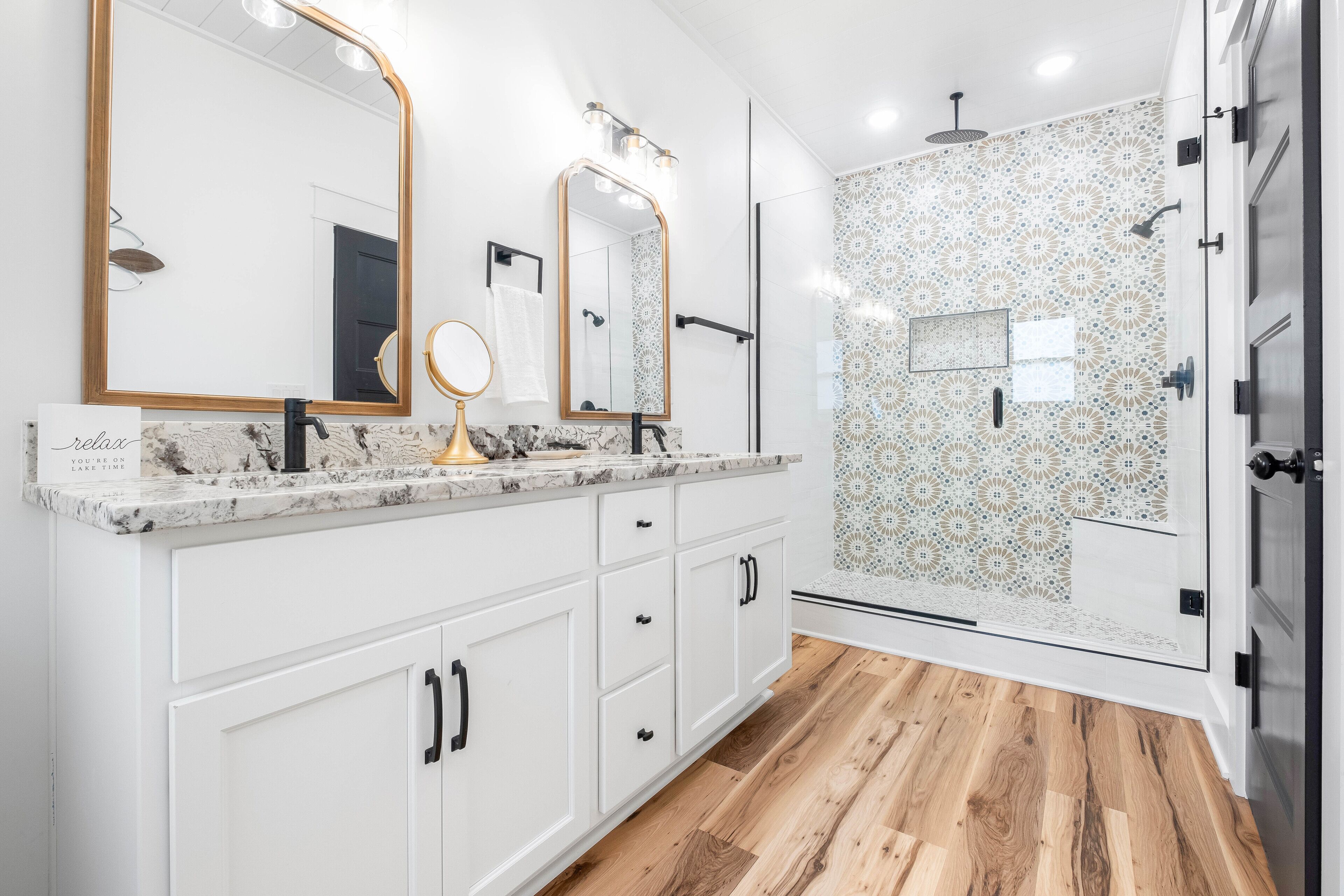 Une salle de bain moderne avec un grand miroir, deux lavabos et un espace douche.