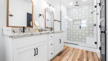 Une salle de bain moderne avec un grand miroir, deux lavabos et un espace douche.