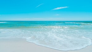 Een strand met helder turquoise water en wit zand.