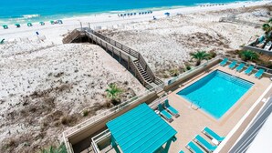 Zwembad met uitzicht op het strand, een houten terras en ligbedden.