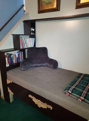 Una stanza piccola e accogliente con un letto a incasso, una libreria e una scala.