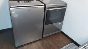 A compact kitchen with two stainless steel appliances, a refrigerator and an oven, against a white wall. - Blue Elephant Cottage (Sullivan)