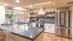 Cocina moderna con una isla grande, electrodomésticos de acero inoxidable y vistas al exterior.