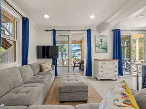 A living room with a grey sofa, a white cabinet, and a TV mounted on the wall. - Lo key cottages estate (Green turtle cay)