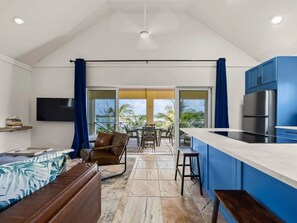 A modern kitchen with a built-in refrigerator, a dining area with a table and chairs, and a balcony with a view of palm trees.