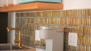 Eine Küche mit einer türkisfarbenen Mikrowelle, einer Kaffeemaschine und einem goldfarbenen Wasserhahn.