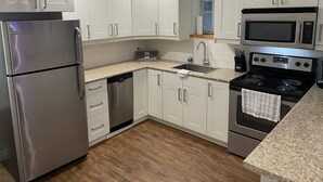 Eine moderne Küche mit weißen Schränken, Edelstahlgeräten, einer Granit Arbeitsplatte und Holzboden.