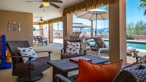 Une terrasse extérieure avec des meubles en osier, un barbecue et une vue sur la piscine.