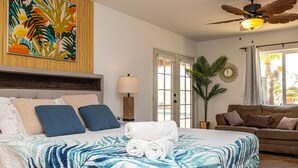 Une chambre avec un lit, un canapé, un ventilateur de plafond et une grande fenêtre.