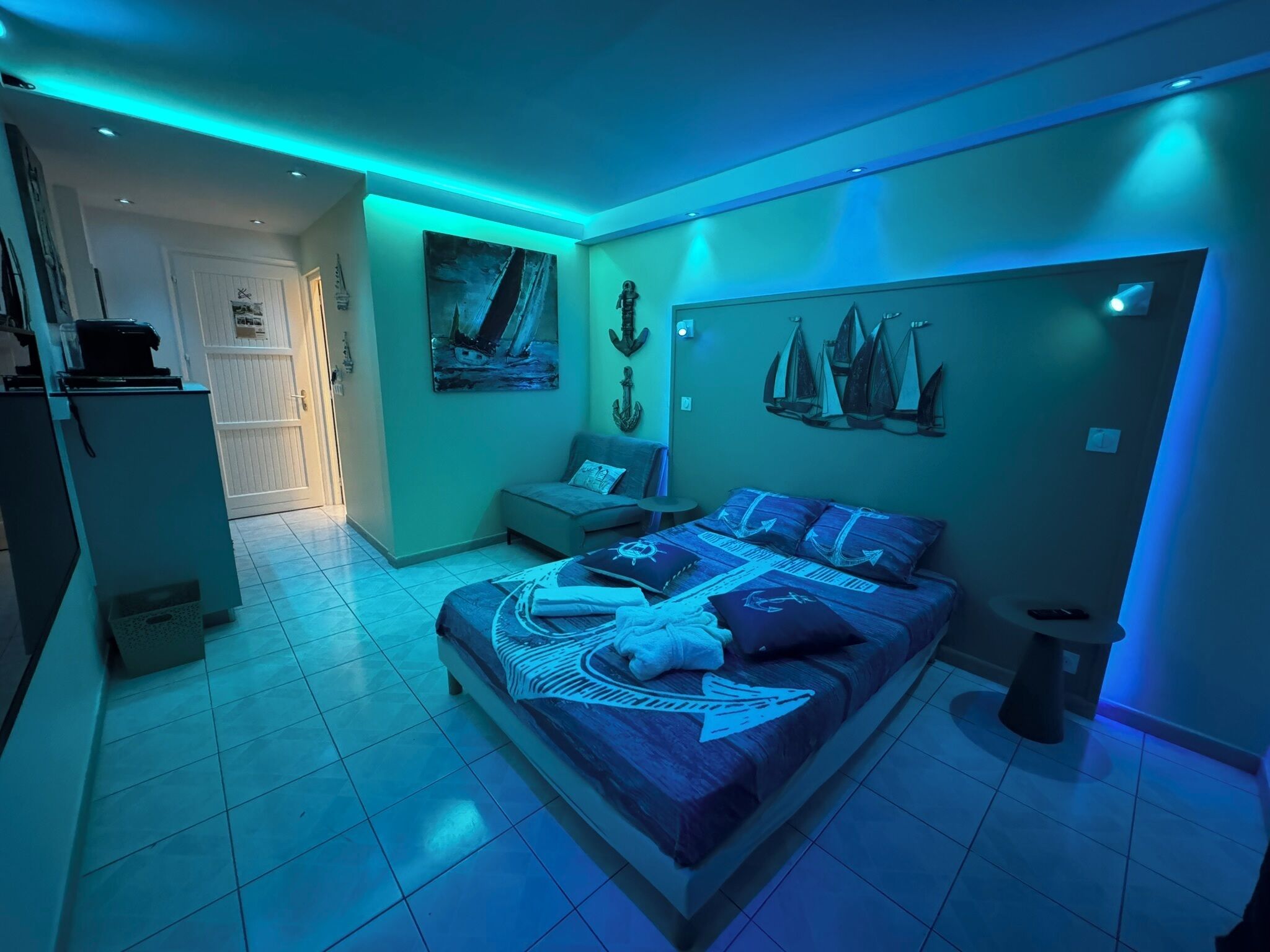 A bedroom with a bed, a desk, and a chair. There is a door leading to another room.