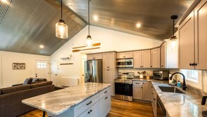 A modern kitchen with a central island, stainless steel appliances, and pendant lighting.