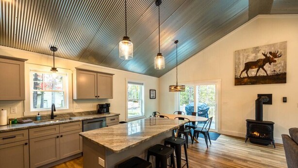 A modern kitchen with a large island, bar stools, and a wood-burning stove.