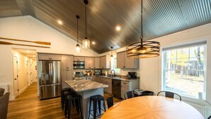 A modern kitchen with stainless steel appliances, a large island, and a dining area with a round table.