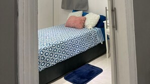A bedroom with a bed, a bedside lamp, and a hanging curtain.