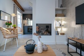Una sala moderna con chimenea, un comedor con sillas de mimbre y una cocina al fondo.