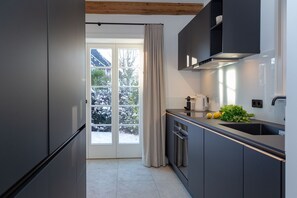 Una cocina moderna con armarios grises, un refrigerador de acero inoxidable, horno empotrado y un lavamanos.