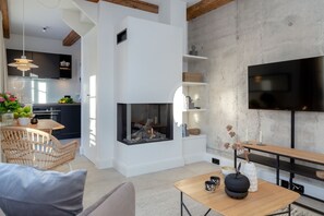 Una sala de estar moderna con chimenea, un comedor y una cocina al fondo.