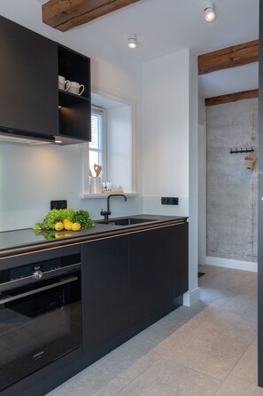 A modern kitchen with dark cabinetry, a built-in oven, and a window above the sink.