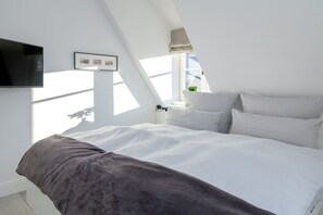 Un dormitorio moderno con cama, paredes blancas y tragaluz.