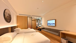 A modern hotel room with two beds, a sofa, a TV, and a mirror. - Changsheng Hotel  (Jiangmen)
