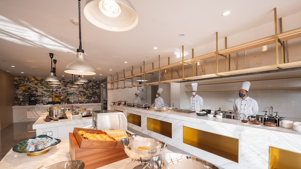 A modern kitchen with marble countertops, gold accents, and chefs in uniform. - Changsheng Hotel  (Jiangmen)